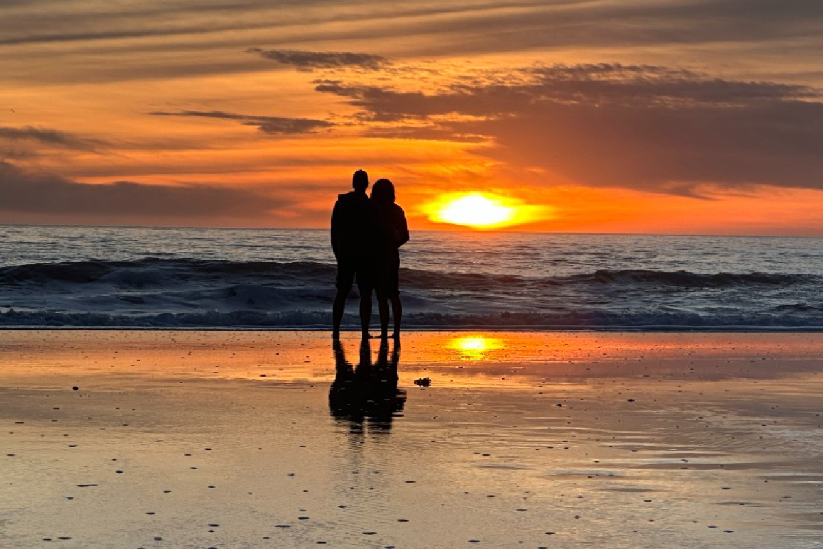 Two people on a beach at sunset